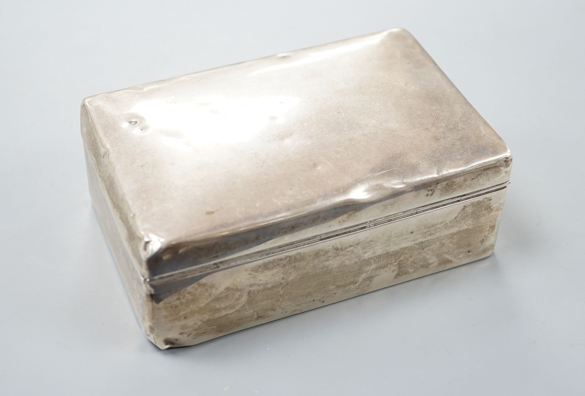 A silver mounted cigarette box, two silver vestas and a silver matchbox sleeve.